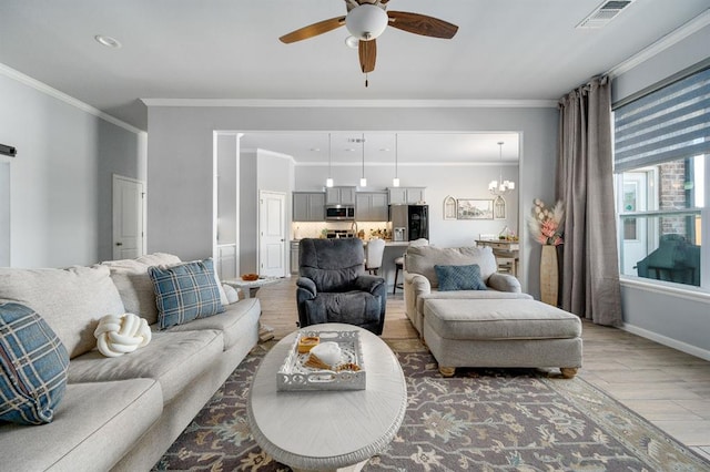 living area with light wood-type flooring, visible vents, ceiling fan with notable chandelier, crown molding, and baseboards