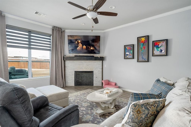 living area with visible vents, crown molding, baseboards, a fireplace, and wood finished floors