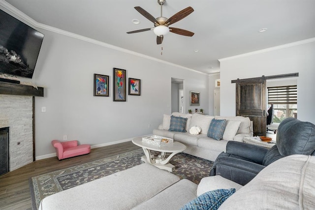 living area with a fireplace, crown molding, wood finished floors, and baseboards