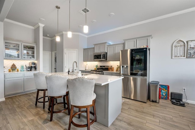 kitchen with a kitchen bar, visible vents, a center island with sink, stainless steel appliances, and light countertops