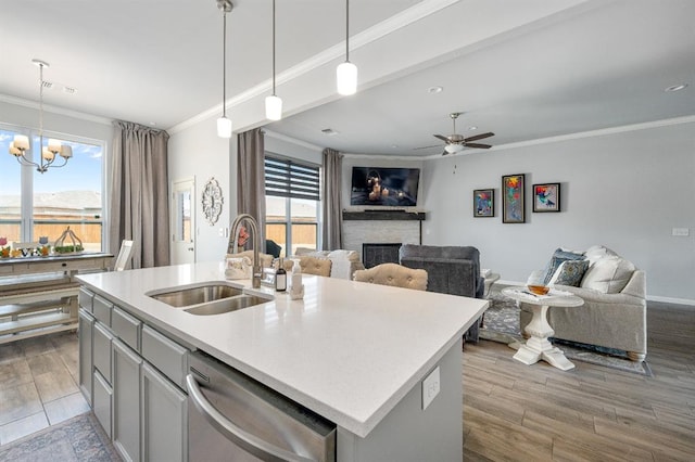 kitchen with ornamental molding, a sink, stainless steel dishwasher, open floor plan, and a fireplace