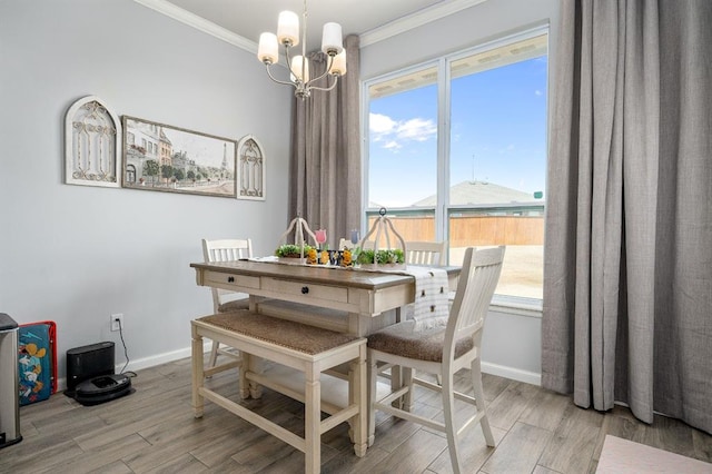 dining room featuring a notable chandelier, light wood-type flooring, baseboards, and ornamental molding