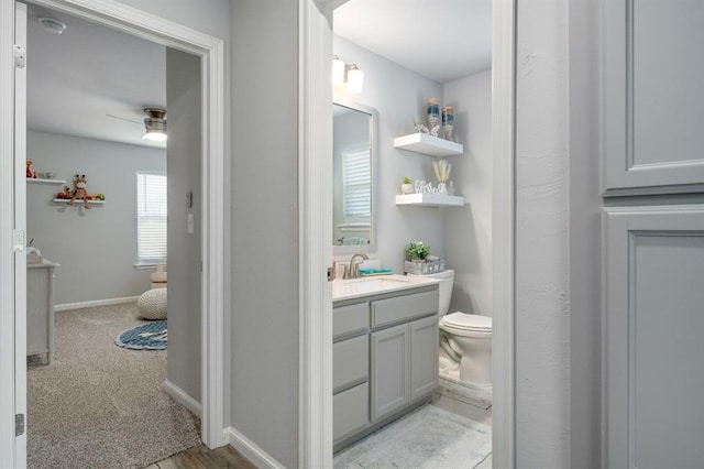 bathroom with baseboards, toilet, and vanity