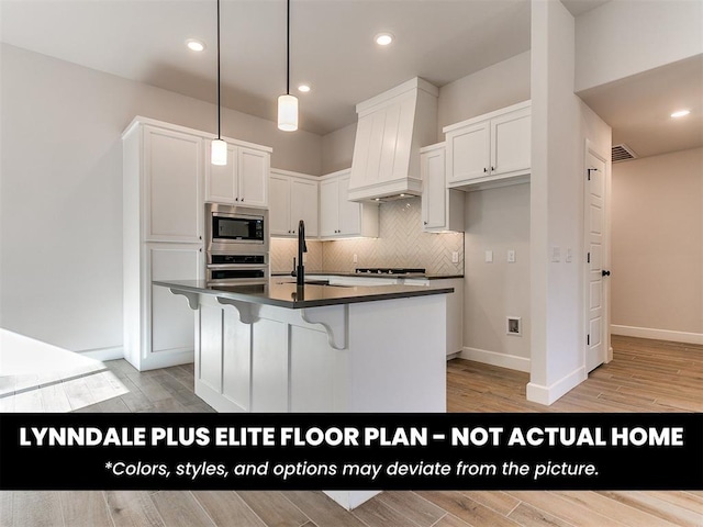 kitchen featuring a sink, appliances with stainless steel finishes, dark countertops, premium range hood, and backsplash