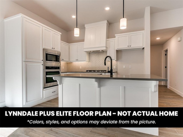 kitchen featuring decorative backsplash, white cabinets, appliances with stainless steel finishes, dark countertops, and hanging light fixtures