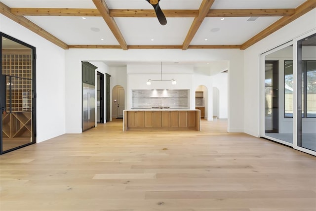 interior space featuring arched walkways, light wood-style flooring, open floor plan, backsplash, and beamed ceiling