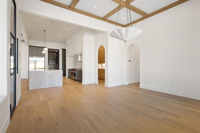 unfurnished living room featuring light wood-type flooring, arched walkways, coffered ceiling, and baseboards