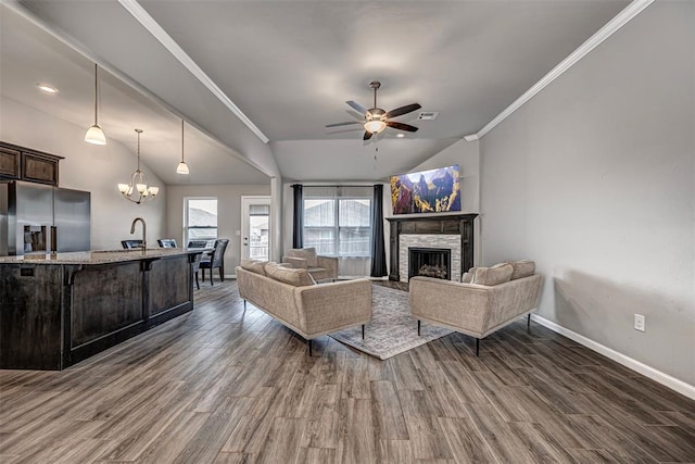 living room featuring dark wood-style floors, a stone fireplace, lofted ceiling, and crown molding