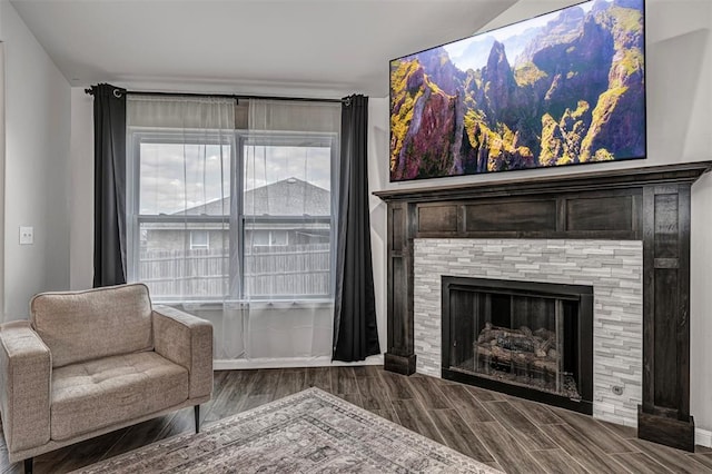 sitting room featuring a tiled fireplace and wood finished floors