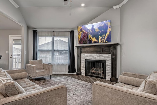 living room featuring vaulted ceiling, a tiled fireplace, wood finished floors, and a ceiling fan