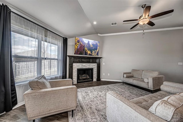 living room with baseboards, visible vents, vaulted ceiling, crown molding, and a fireplace