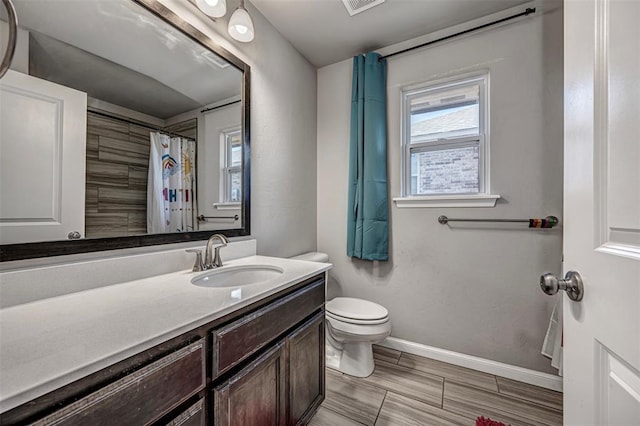 bathroom featuring visible vents, baseboards, vanity, and toilet