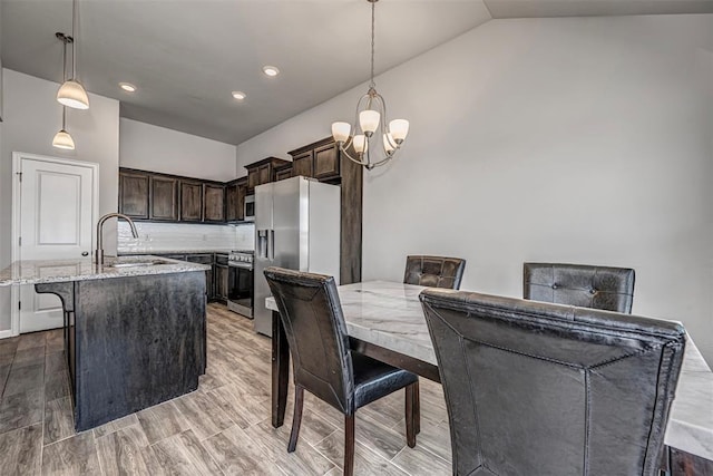 dining room featuring light wood-type flooring, a chandelier, vaulted ceiling, and recessed lighting