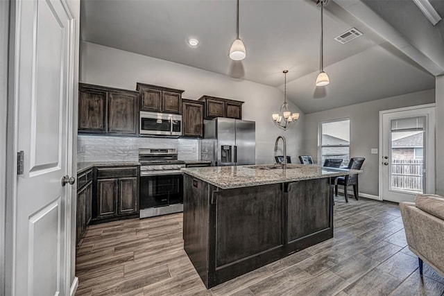 kitchen with light stone counters, visible vents, backsplash, appliances with stainless steel finishes, and a sink