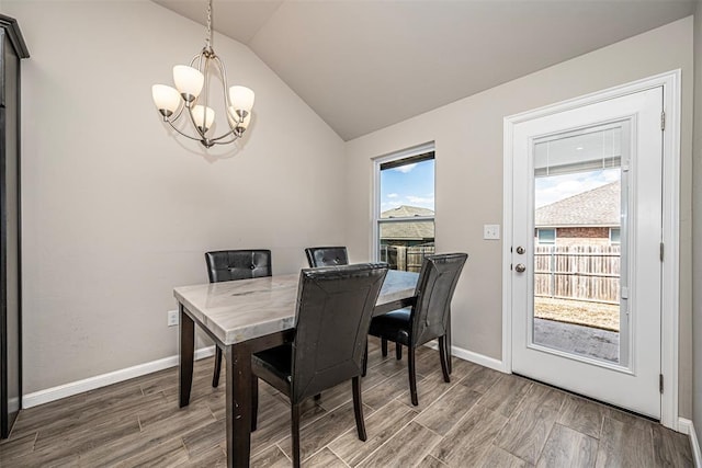 dining area with lofted ceiling, a notable chandelier, baseboards, and wood finished floors