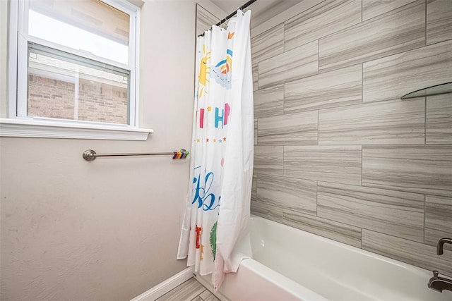 bathroom featuring baseboards and shower / tub combo with curtain