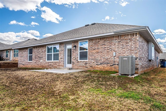 back of house featuring central AC unit, a patio, roof with shingles, a yard, and brick siding