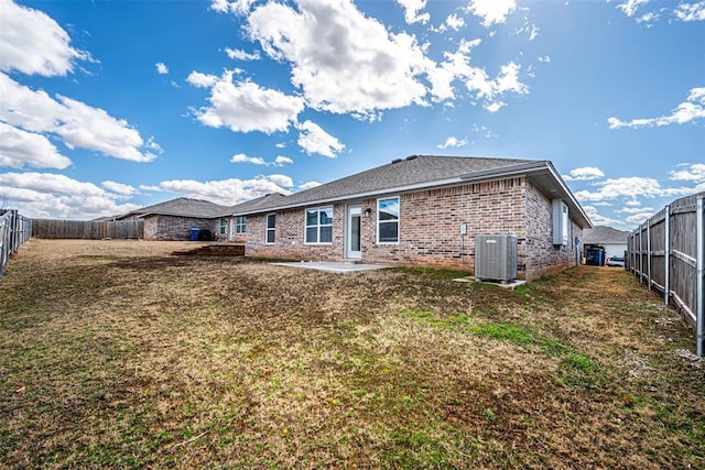 back of property featuring a fenced backyard, brick siding, a lawn, and central AC unit