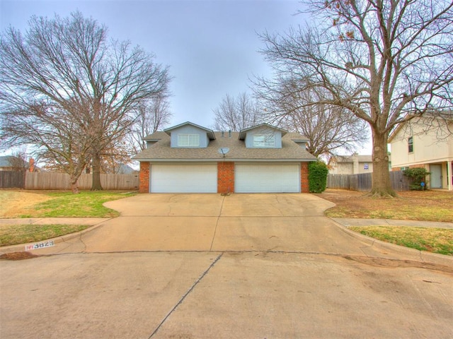 view of front facade featuring a garage, driveway, brick siding, and fence