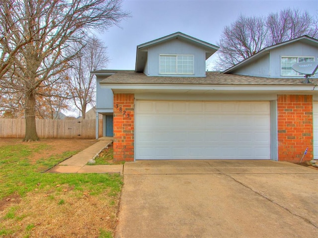 traditional-style home featuring a garage, fence, concrete driveway, and brick siding