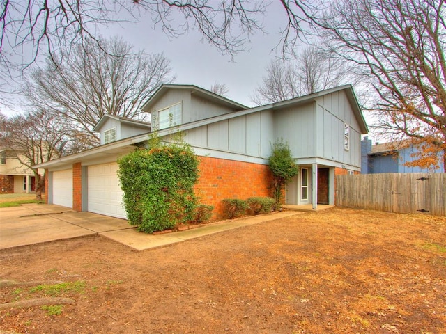 view of front of house featuring driveway, brick siding, an attached garage, and fence