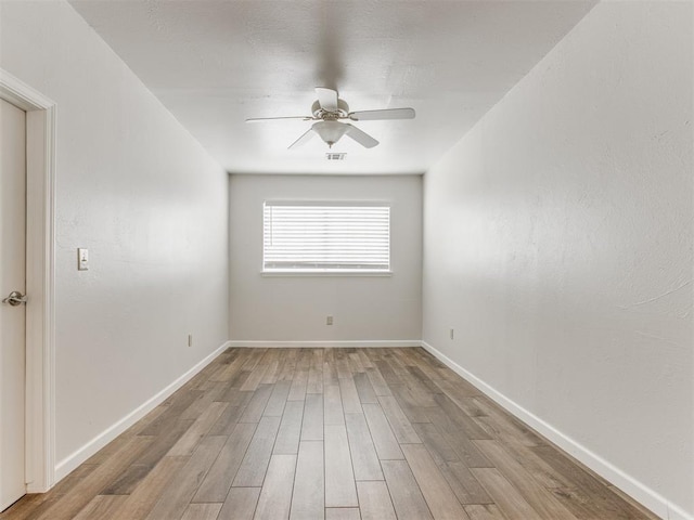 unfurnished room featuring ceiling fan, visible vents, baseboards, and wood finished floors