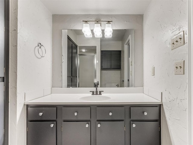 bathroom featuring a stall shower, a textured wall, and vanity