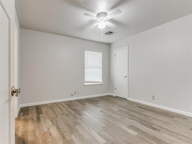 empty room with light wood finished floors, baseboards, visible vents, and a ceiling fan