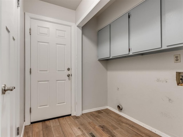 clothes washing area featuring light wood-type flooring, cabinet space, electric dryer hookup, and baseboards