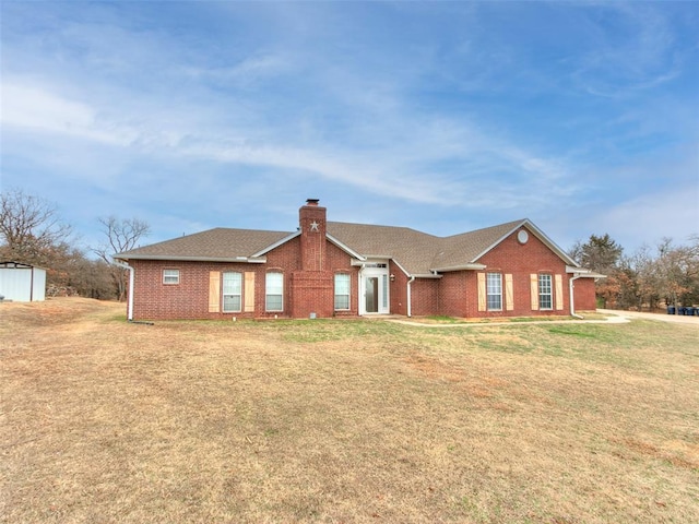 ranch-style house featuring a front yard, brick siding, a chimney, and roof with shingles