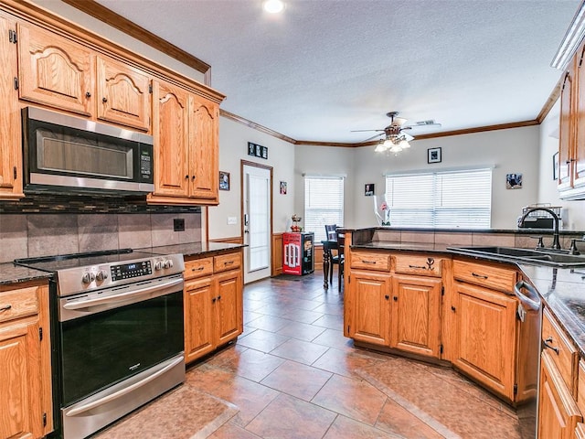 kitchen featuring crown molding, appliances with stainless steel finishes, decorative backsplash, and a sink