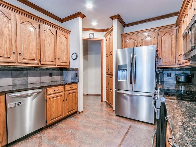 kitchen featuring ornamental molding, appliances with stainless steel finishes, dark stone counters, and tasteful backsplash