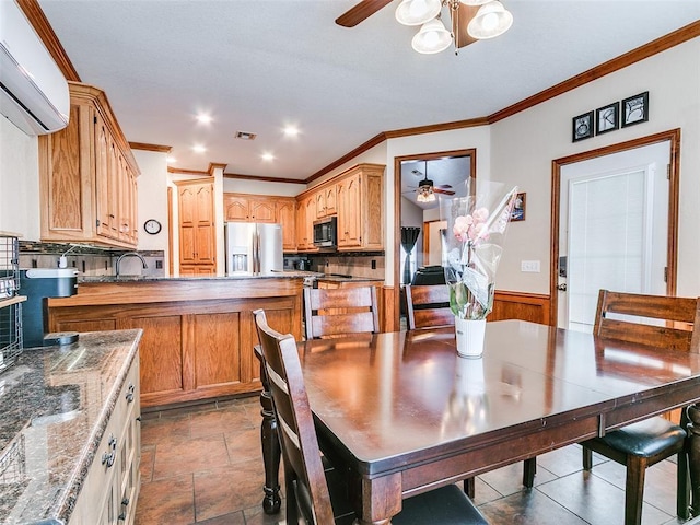 dining space featuring visible vents, a ceiling fan, wainscoting, ornamental molding, and a wall mounted air conditioner