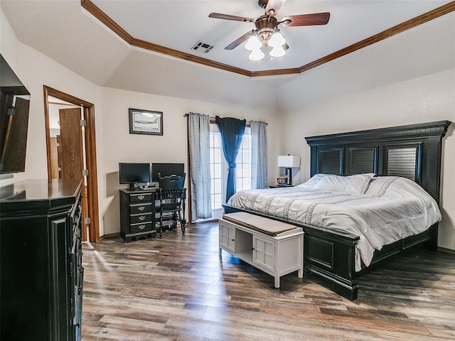 bedroom with a tray ceiling, ornamental molding, wood finished floors, and visible vents