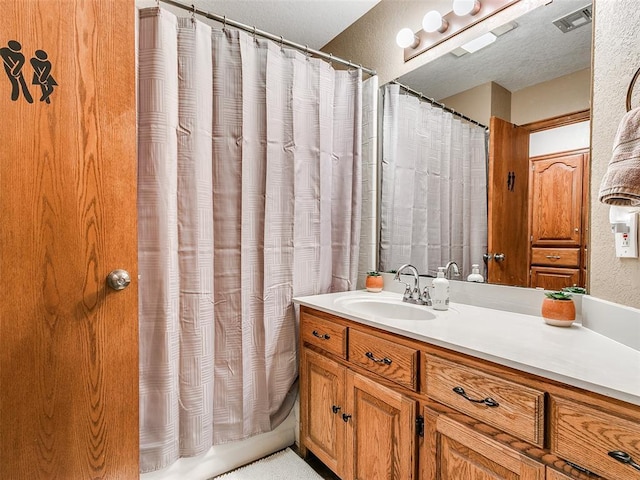 bathroom featuring a shower with shower curtain, visible vents, a textured ceiling, and vanity