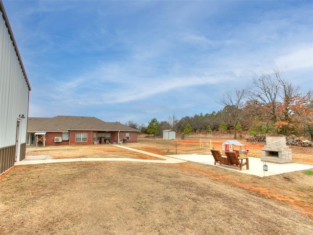 view of yard featuring an outdoor stone fireplace and a patio