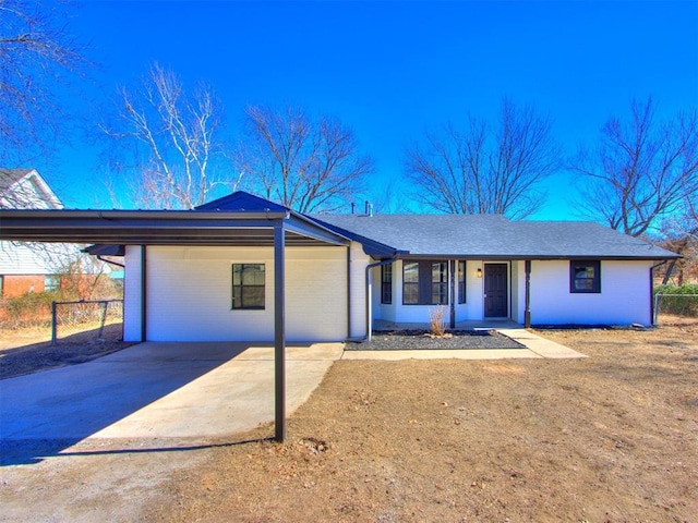 view of front of house with brick siding, fence, and driveway