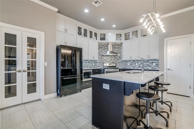 kitchen featuring appliances with stainless steel finishes, wall chimney exhaust hood, french doors, and a sink