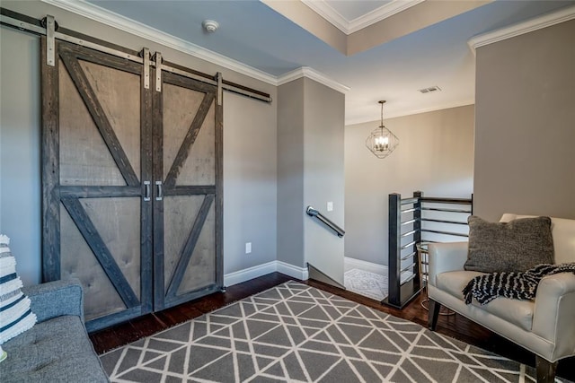 foyer featuring a barn door, wood finished floors, ornamental molding, and a chandelier