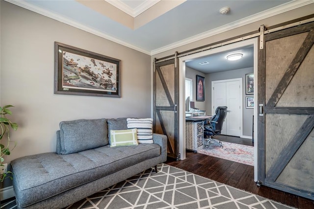 living area with a barn door, baseboards, crown molding, and hardwood / wood-style flooring