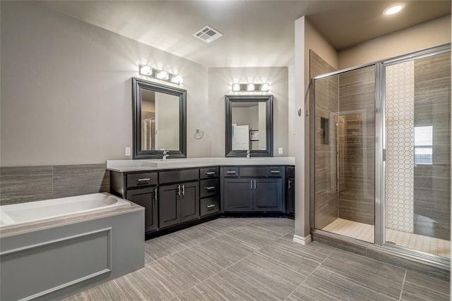 full bath featuring tile patterned flooring, visible vents, a shower stall, a garden tub, and double vanity