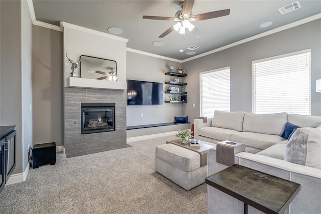 living area with a tiled fireplace, visible vents, carpet flooring, and ornamental molding