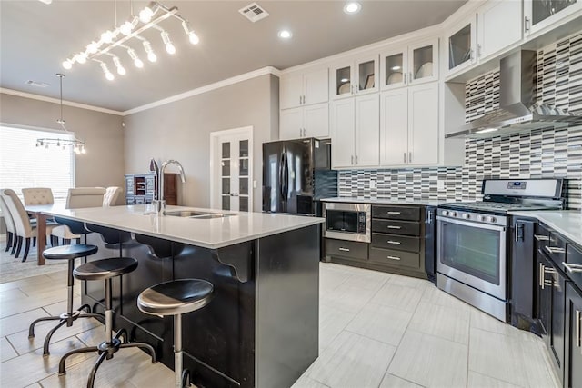 kitchen with visible vents, appliances with stainless steel finishes, white cabinetry, wall chimney exhaust hood, and a sink