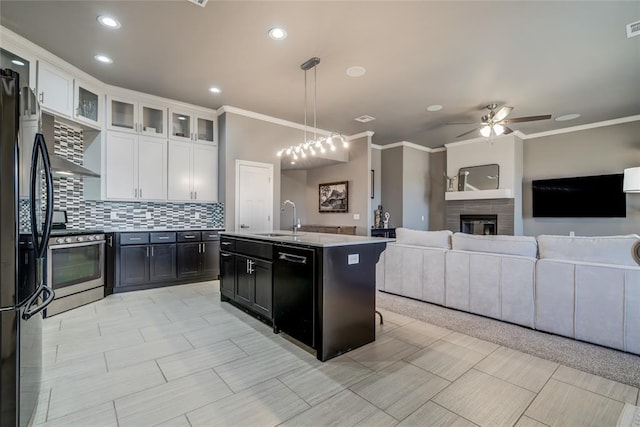 kitchen with black appliances, a sink, tasteful backsplash, open floor plan, and white cabinetry