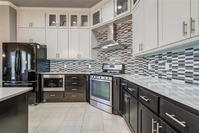 kitchen with white cabinetry, backsplash, appliances with stainless steel finishes, and wall chimney range hood