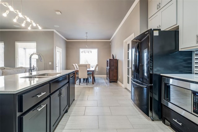 kitchen featuring a sink, stainless steel microwave, dishwasher, and hanging light fixtures