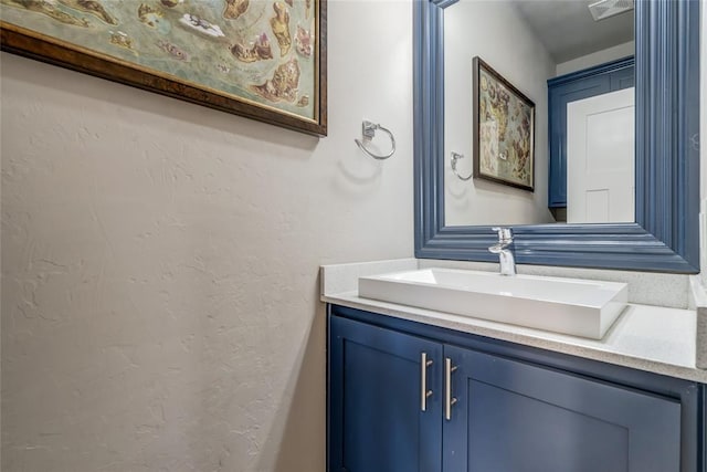 bathroom featuring visible vents, vanity, and a textured wall