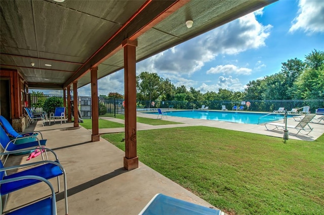 pool with a patio, a lawn, and fence