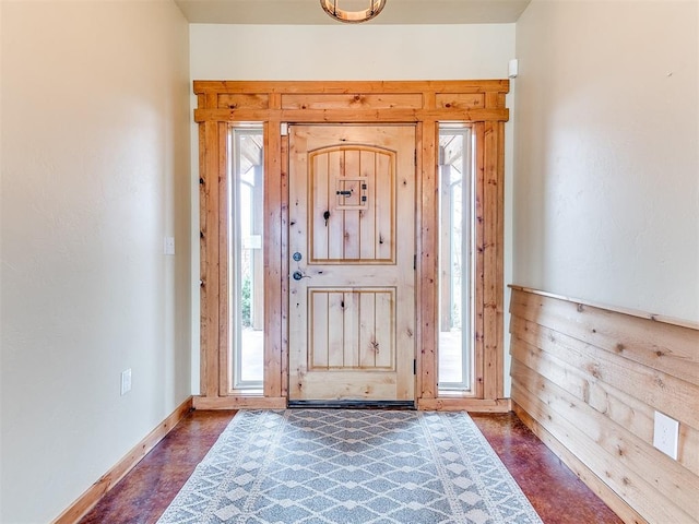 entrance foyer featuring wooden walls and baseboards