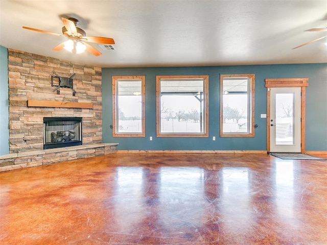 unfurnished living room with visible vents, baseboards, a ceiling fan, concrete flooring, and a stone fireplace